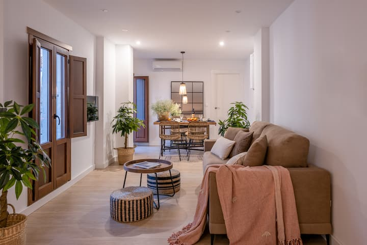 Zona de estar de Alcazaba con sofá cama y comedor al fondo