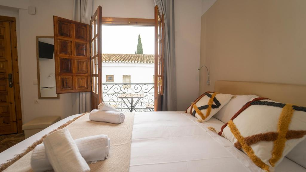 Cama doble con balcón abierto de una habitación de Carmen San Luis